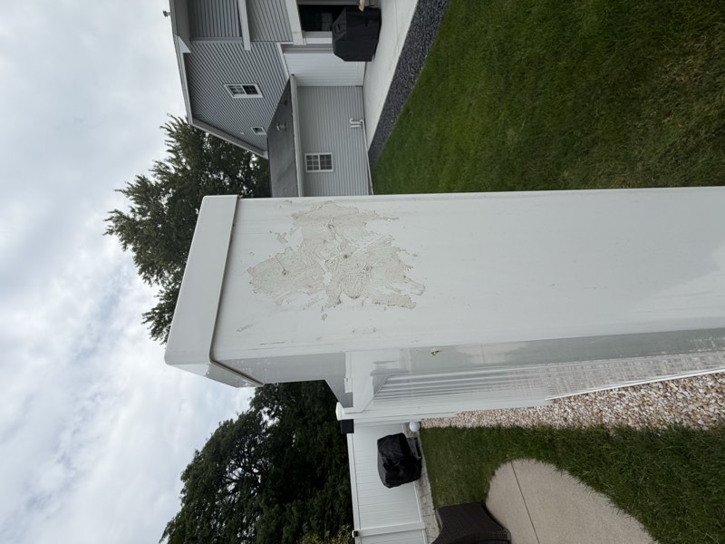 Caulk troweled across the face of a white vinyl fence post covering drilled holes.