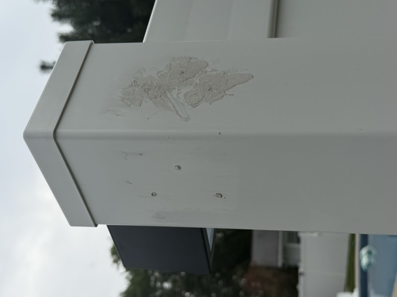 A close view of caulk smeared over drilled holes on the corner of a fence post.
