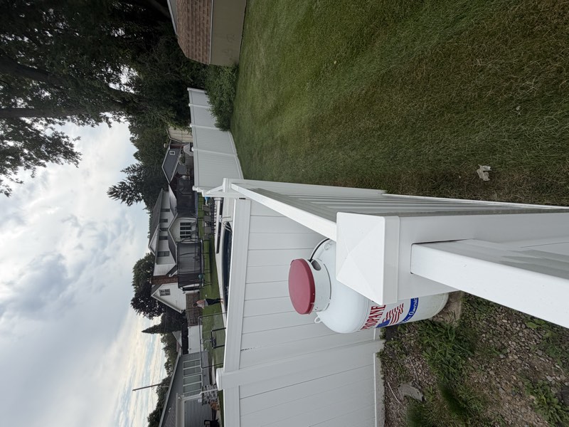 A wide view of the backyard showing the vinyl fence enclosing an in-ground swimming pool.